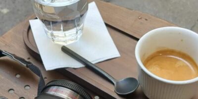 une tasse de café sur une table avec un verre d'eau et un appareil photo