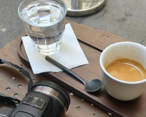 une tasse de café sur une table avec un verre d'eau et un appareil photo